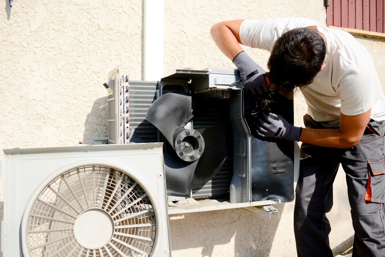 Technician repairing outdoor air conditioning unit